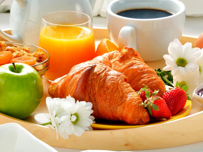 Bandeja de desayuno corporativo con croissant, café, jugo natural y fruta en Pasto